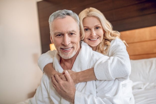 Pessoas felizes. Casal de roupão de banho aproveitando o tempo que passa junto e parecendo feliz