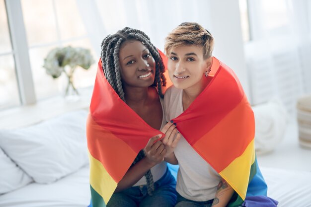 Foto pessoas felizes. duas meninas com uma bandeira de arco-íris sorrindo positivamente