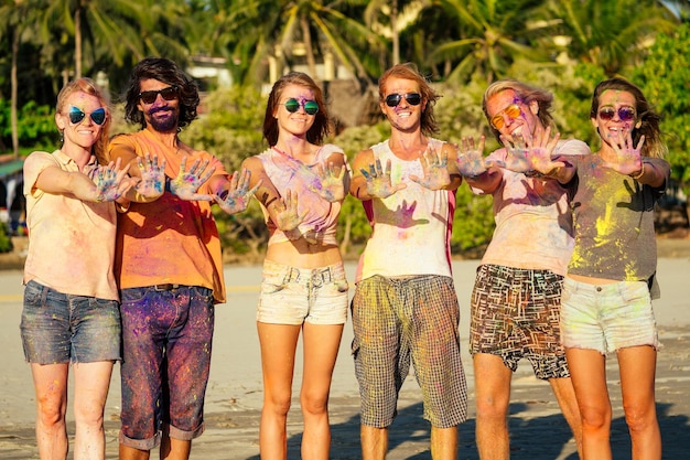 Pessoas felizes em tinta colorida holi brincam na praia em festa na praia de Goa, Índia