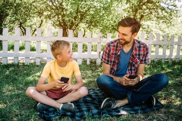 Pessoas felizes estão sentados no cobertor no parque