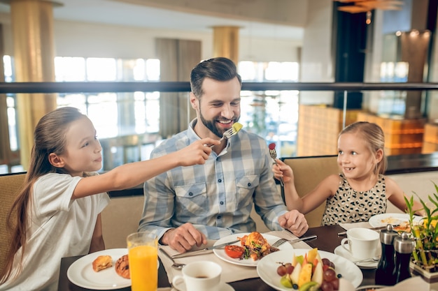 Pessoas felizes. Família sorridente, sentada à mesa e parecendo feliz