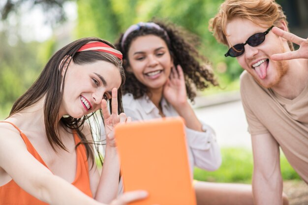 Pessoas felizes. Jovens alegres otimistas em um humor brincalhão tirando selfie no tablet e descansando na natureza em um dia ensolarado