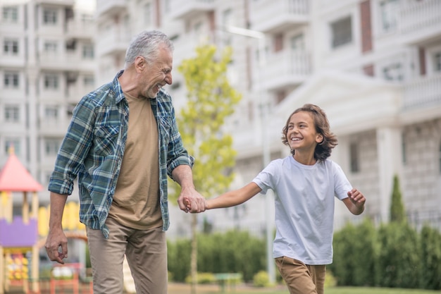 Pessoas felizes. Pai e filho caminhando juntos de mãos dadas e parecendo felizes