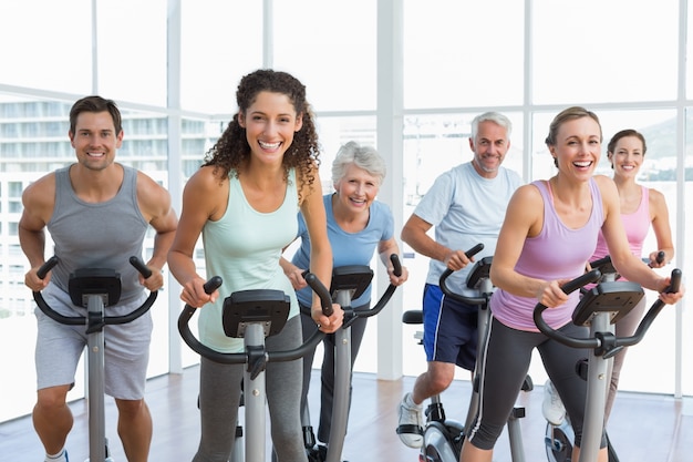 Pessoas felizes que trabalham na classe de spinning