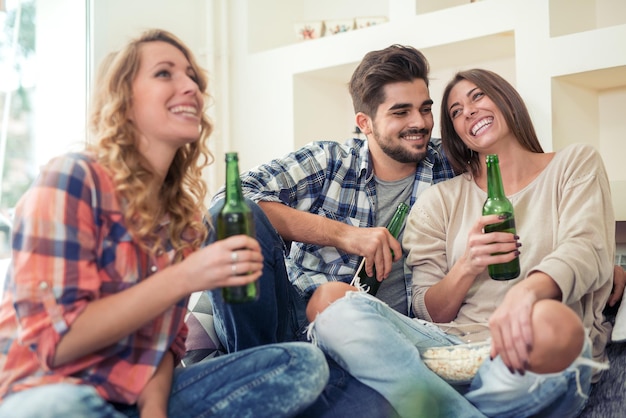 Pessoas felizes se divertindo, bebendo cerveja juntos em casa.