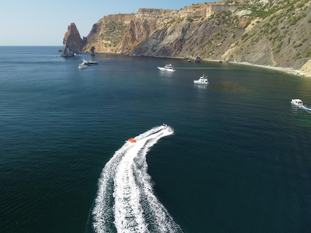 Pessoas felizes vão nadar em um colchão de ar atrás de um turista de jet ski montando o inflável