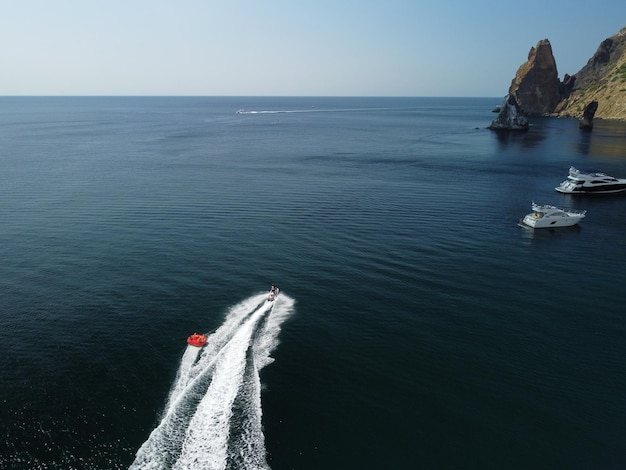 Pessoas felizes vão nadar em um colchão de ar atrás de um turista de jet ski montando o inflável