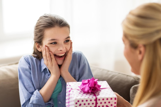 pessoas, feriados e conceito de família - garota feliz recebendo presente de aniversário da mãe em casa