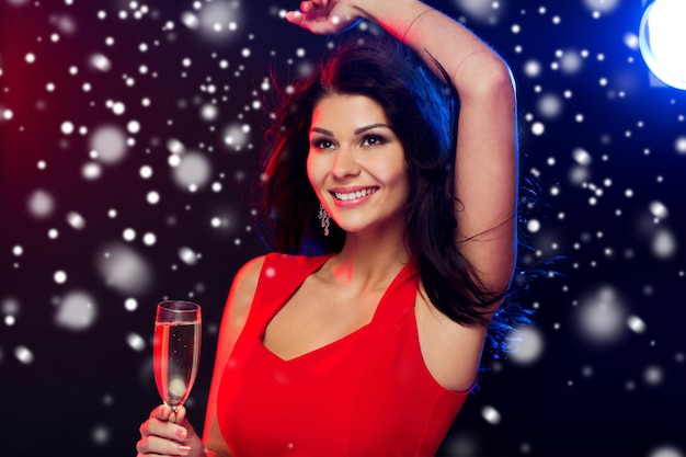 pessoas, férias de inverno, festa, estilo de vida noturno e conceito de lazer - bela mulher sexy vestido vermelho com taça de champanhe dançando na boate sobre a neve