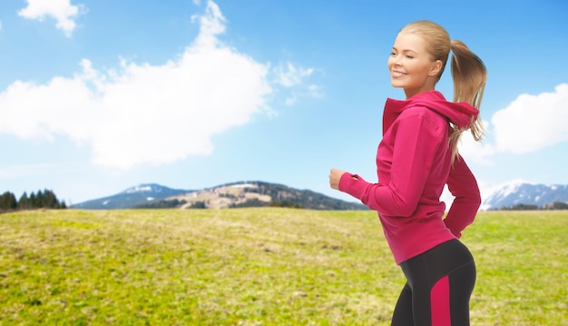 Pessoas, fitness, esporte e estilo de vida saudável - mulher desportiva feliz correndo ou correndo sobre a natureza