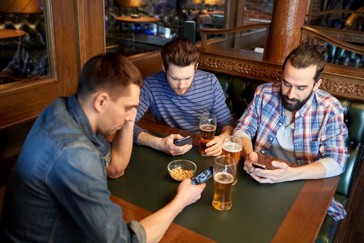 Foto pessoas, homens, lazer, amizade e conceito de comunicação - amigos do sexo masculino com smartphones bebendo cerveja no bar ou pub