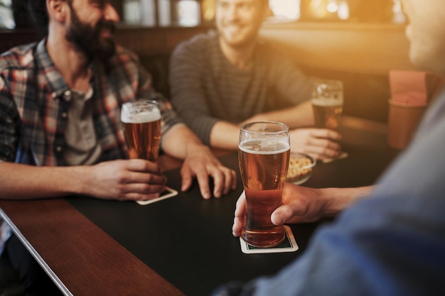 pessoas, homens, lazer, amizade e conceito de comunicação - close-up de amigos do sexo masculino felizes bebendo chope no bar ou pub