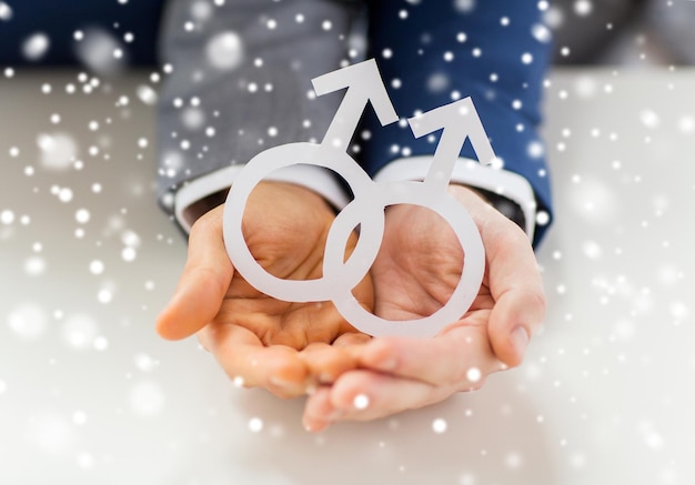 pessoas, homossexualidade, casamento entre pessoas do mesmo sexo e conceito de amor - close-up de casal gay masculino feliz segurando símbolo de amor de recorte de papel sobre efeito de neve