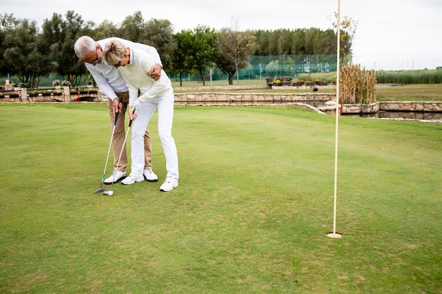 Pessoas idosas aproveitando o tempo livre na aposentadoria e aprendendo a jogar golfe no campo