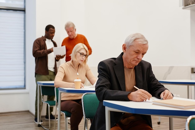 Pessoas idosas escrevendo teste em sala de aula