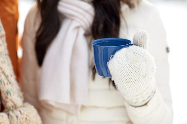 pessoas, inverno, bebidas e conceito de temporada - close-up da mulher segurando a xícara de chá quente