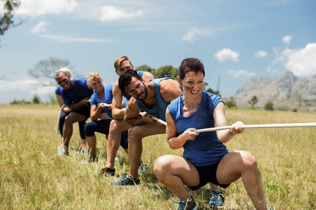 Foto pessoas jogando cabo de guerra durante o curso de treinamento de obstáculos