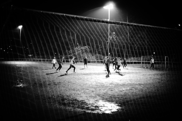 Foto pessoas jogando futebol no campo à noite