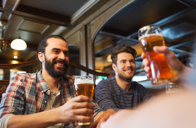 Pessoas, lazer, amizade e conceito de despedida de solteiro - amigos do sexo masculino felizes bebendo cerveja no bar ou pub