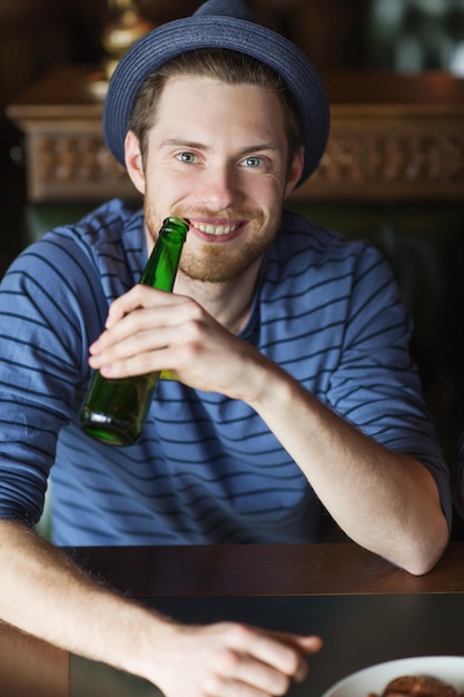 pessoas, lazer, celebração e conceito de despedida de solteiro - jovem feliz bebendo cerveja no bar ou pub