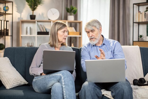 Pessoas maduras lendo artigo no laptop na sala de estar