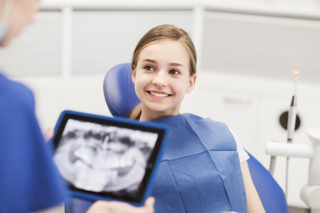 pessoas, medicina, estomatologia, tecnologia e conceito de cuidados de saúde - dentista com raio-x no computador tablet pc e paciente menina