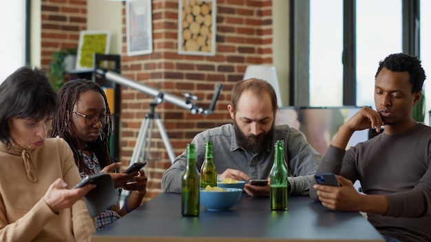 Pessoas milenares navegando pela internet no smartphone em vez de conversar umas com as outras em casa reunidas. grupo de amigos navegando no site de mídia social na rede de telefonia móvel.