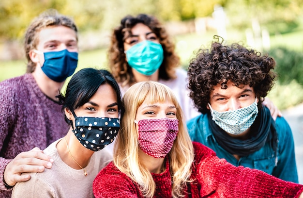 Foto pessoas multirraciais fazendo selfie usando máscara facial e roupas de primavera