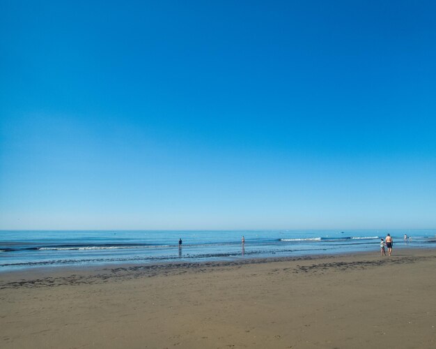 Pessoas na costa na praia em um dia de verão ensolarado conceito de verão