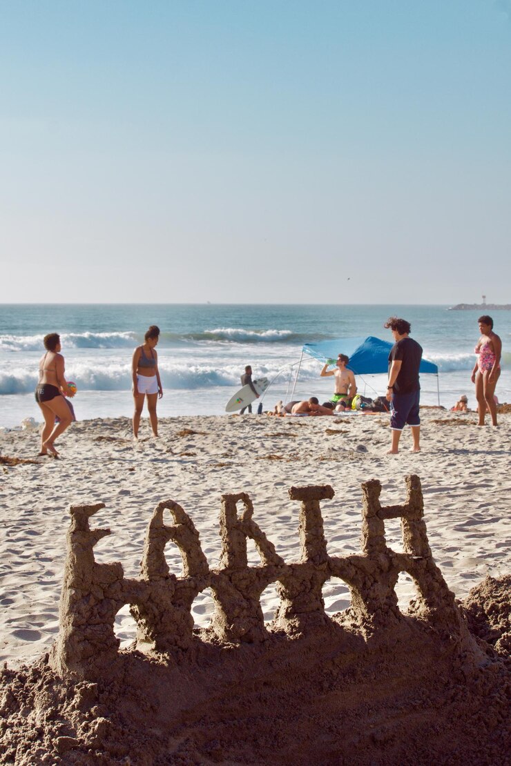 Foto pessoas na praia contra o céu com castelo de areia em primeiro plano