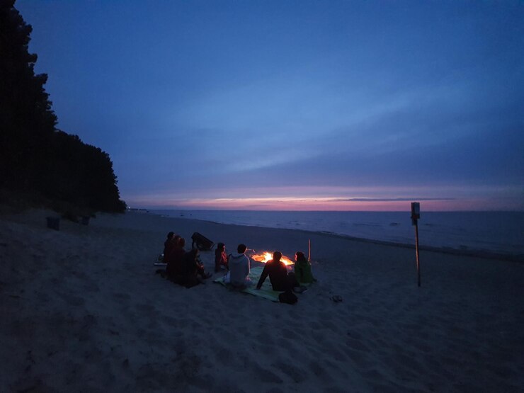 Foto pessoas na praia contra o céu durante o pôr do sol