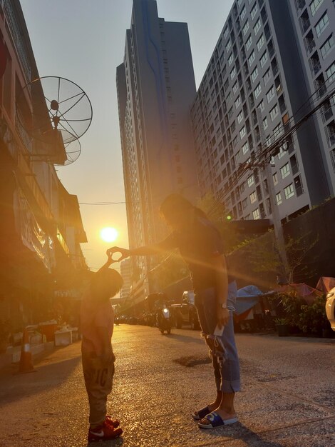 Pessoas na rua em meio a edifícios na cidade durante o pôr do sol