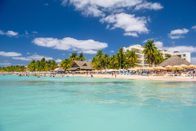 Pessoas nadando perto da praia de areia branca com bar de bangalô de guarda-chuvas e palmeiras de coco mar turquesa do Caribe Ilha de Isla Mujeres Mar do Caribe Cancun Yucatan México