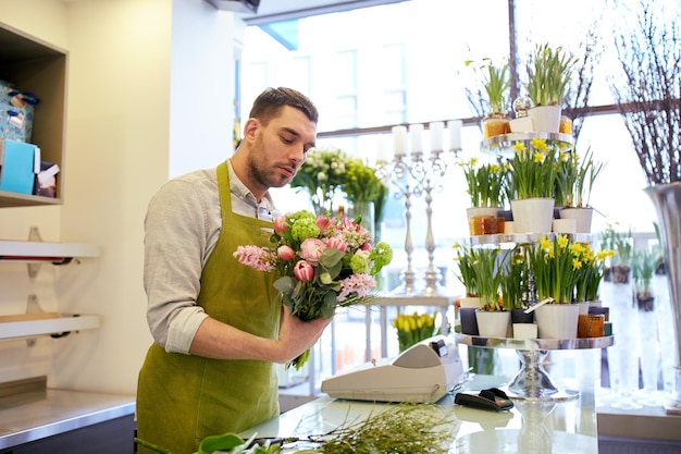 pessoas, negócios, venda e conceito de floricultura - homem florista fazendo cacho na floricultura