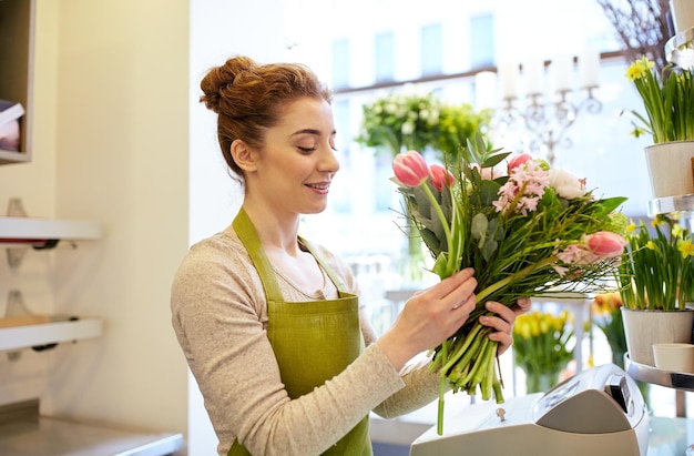pessoas, negócios, venda e conceito de floricultura - mulher florista sorridente feliz fazendo cacho na floricultura