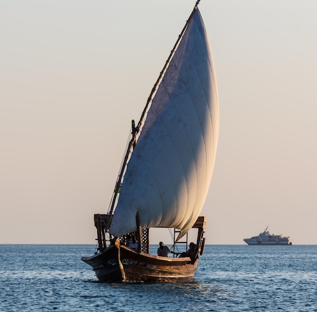 Pessoas no barco navegando ao pôr do sol Uma balsa está no horizonte Zanzibar Tanzânia