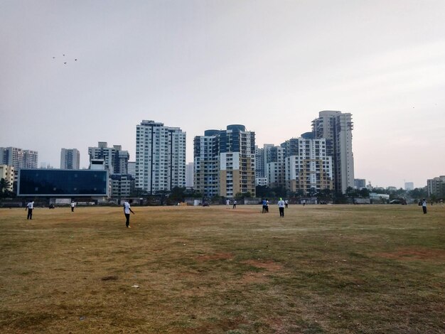 Foto pessoas no campo contra edifícios na cidade