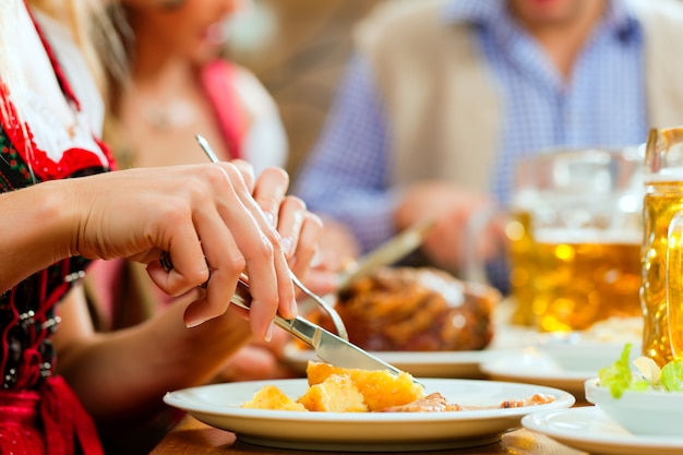 Pessoas que comem porco assado no restaurante da Baviera