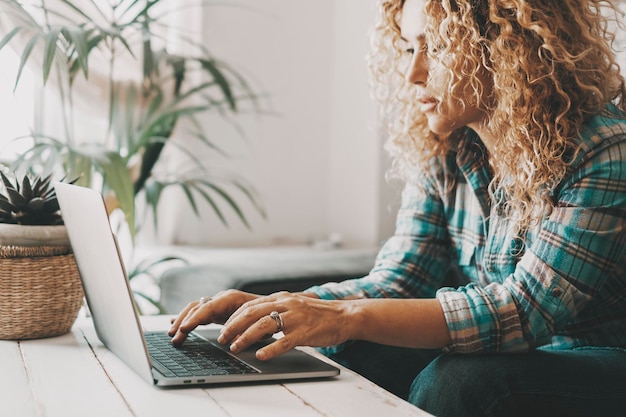 Pessoas que trabalham no computador em casa Uma mulher escreve e usa laptop com conexão on-line à Internet Mulher moderna usa notebook e trabalha Atividade de lazer interna e tecnologia Pesquisando na web