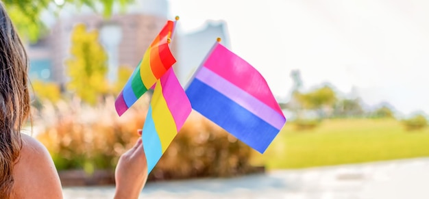 Pessoas queer de gênero agitam bandeiras do arco-íris do orgulho gay LGBTQ em um evento de orgulho Foco seletivo