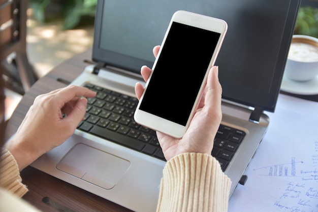 Pessoas, segurando o telefone móvel esperto, olhando na tela e trabalhando no computador