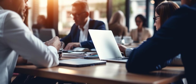 pessoas sentadas em uma mesa com um laptop e um homem de fato com um laptop no fundo