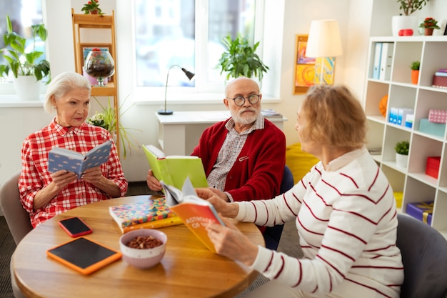 Pessoas simpáticas falando sobre diferentes livros enquanto estão sentadas à mesa