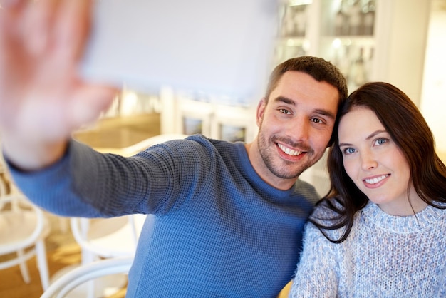 pessoas, tecnologia e conceito de namoro - casal feliz tirando selfie de smartphone no café ou restaurante