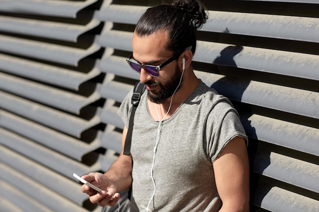 pessoas, tecnologia, viagens e turismo - homem com fones de ouvido, smartphone e bolsa ouvindo música na rua da cidade