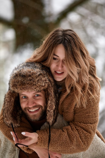 Pessoas temporada amor e conceito de lazer casal feliz abraçando e rindo ao ar livre no inverno Casal abraçando e se divertindo no parque de inverno nevado