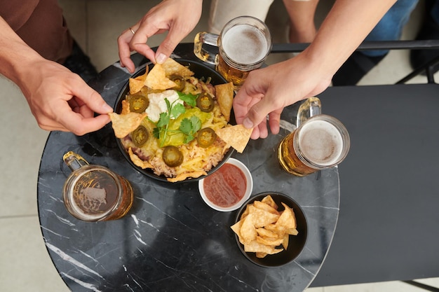 Pessoas tomando cervejas com lanche mexicano