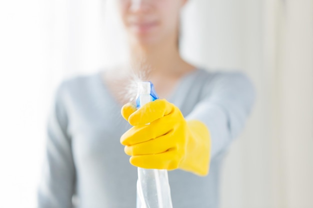 pessoas, trabalho doméstico e conceito de limpeza - close-up de uma mulher feliz com spray de limpeza em casa