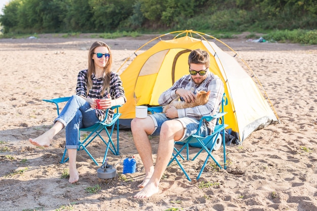 Pessoas, turismo de verão e o conceito de natureza - jovem casal bebendo chá perto da tenda.