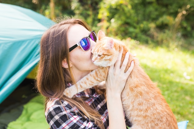 Pessoas, turismo de verão e o conceito de natureza - jovem mulher com um gato perto da tenda.